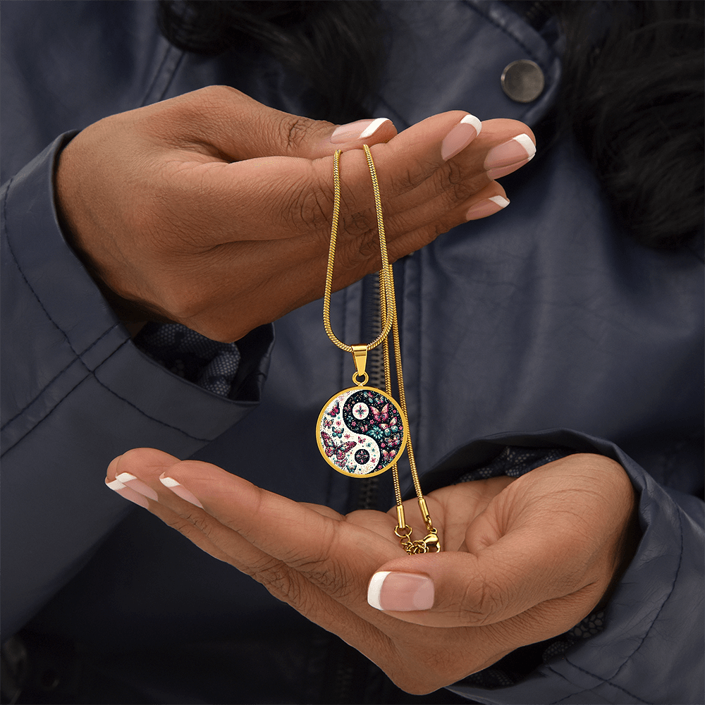 Gold necklace with round Yin Yang pendant featuring pink butterfly accents and floral designs.