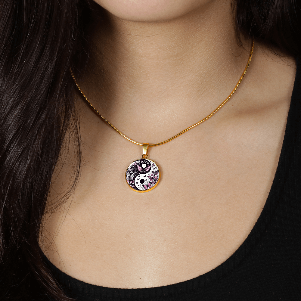 Gold necklace with circular yin yang pendant decorated with violet butterflies and small crystals.