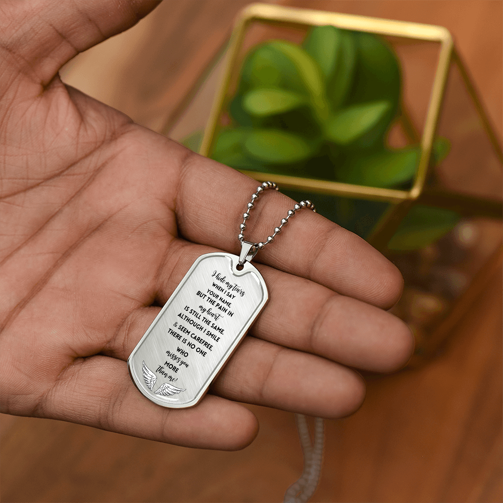 Silver military chain necklace with engraved memorial dog tag held in hand.