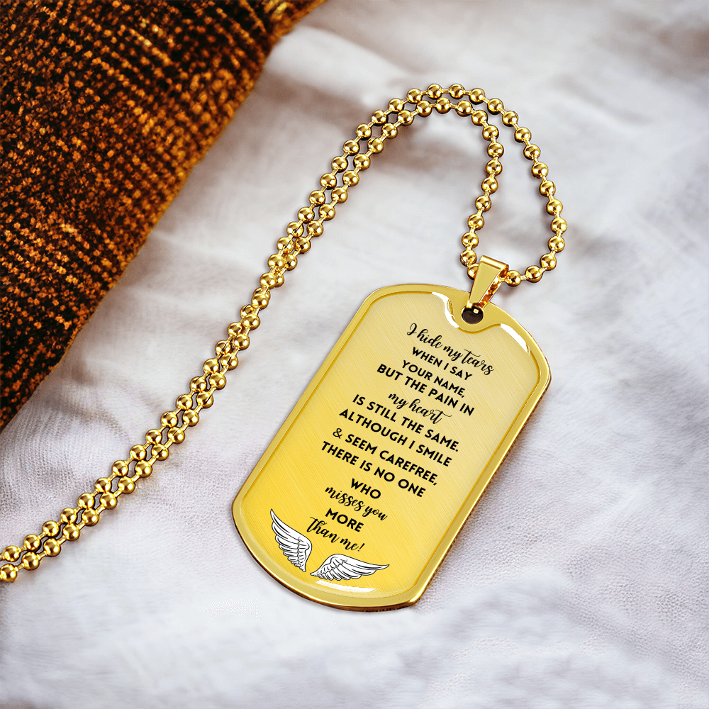 Gold military dog tag necklace with engraved memorial poem and angel wings on white fabric background.