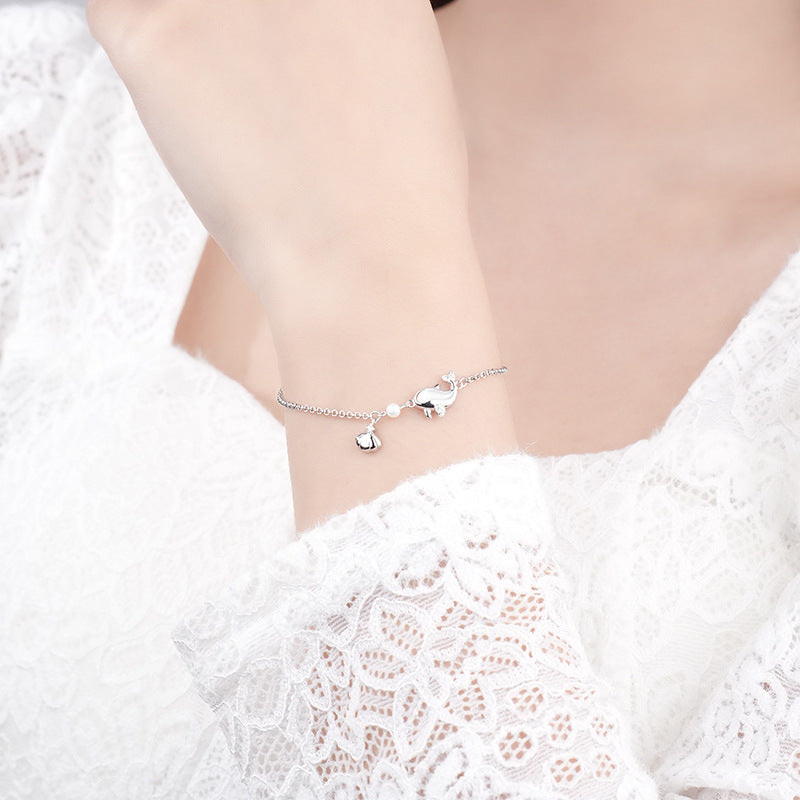 Elegant 925 sterling silver dolphin bracelet with white gold plating on a delicate chain, showcased on a wrist against white lace background, highlighting its dainty charm and lustrous finish