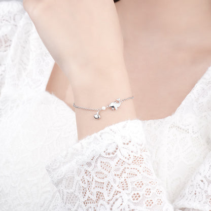 Elegant 925 sterling silver dolphin bracelet with white gold plating on a delicate chain, showcased on a wrist against white lace background, highlighting its dainty charm and lustrous finish