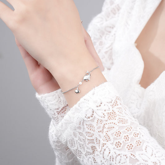 Elegant 925 sterling silver dolphin bracelet on wrist, white gold plated, delicate chain with small dolphin charms, showcased against white lace sleeve, perfect for fashion-forward jewelry lovers